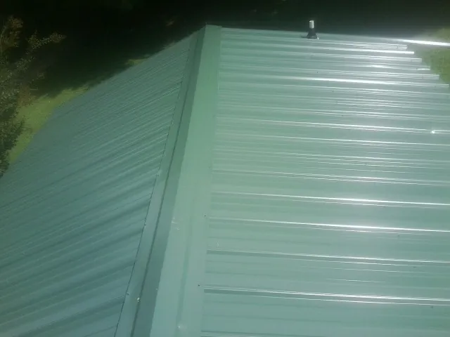 New green metal panels meeting at the ridge of a roof — Flat Roof Repair work by our crew in Palm Bay