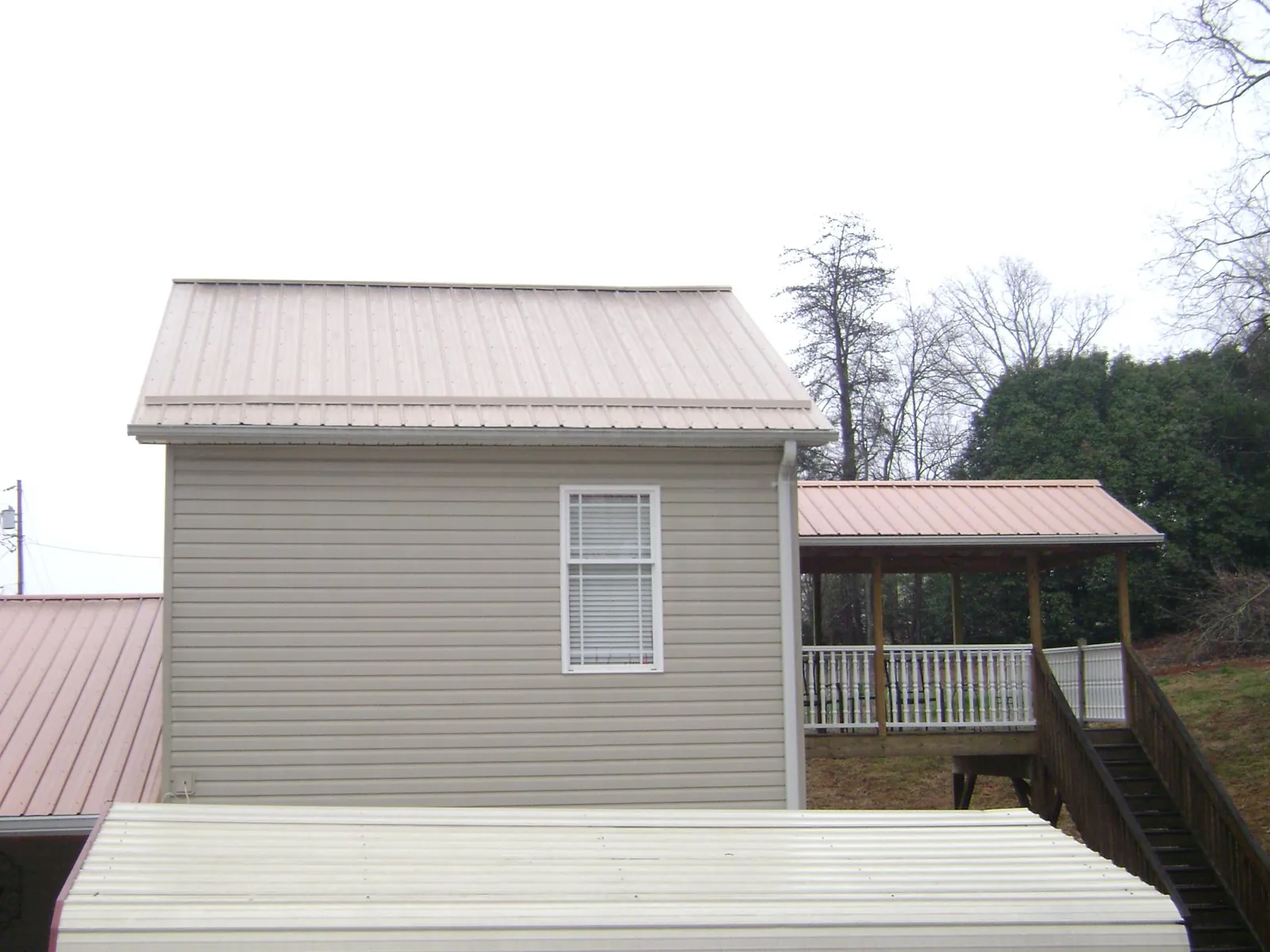 Tan metal roofs on a two story addition and attached porch, from a Roof Replacement job in Palm Bay