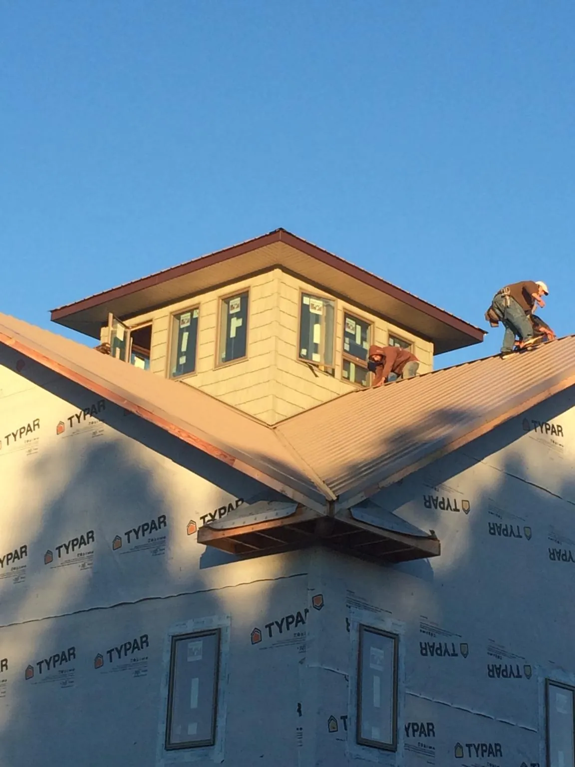 Roofers working around a rooftop cupola on a new metal roof at sunset — Roof Waterproofing in Palm Bay by Roofing Brothers